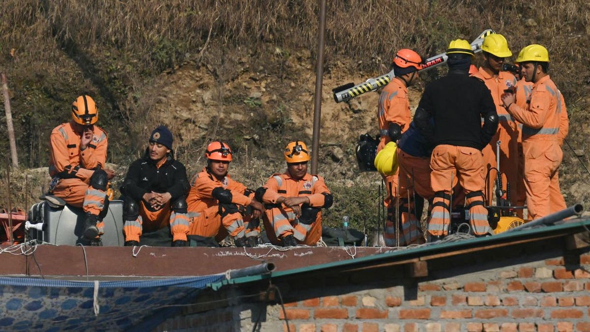 Rescue workers break as they prepare for vertical drilling to reach trapped workers in Indian tunnel